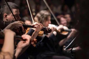 Gros plan de trois violonistes en train de jouer dans un orchestre symphonique
